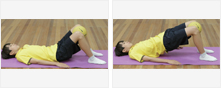 남학생이 매트 위에 등과 팔을 바닥에 붙인 채로 누워서 다리를 구부리고 있고 이어서 엉덩이를 들어올리고 있다.