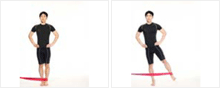 남성이 옆으로 서서 탄력밴드를 한쪽 발목에 걸고 몸 바깥쪽으로 당기고 있다.